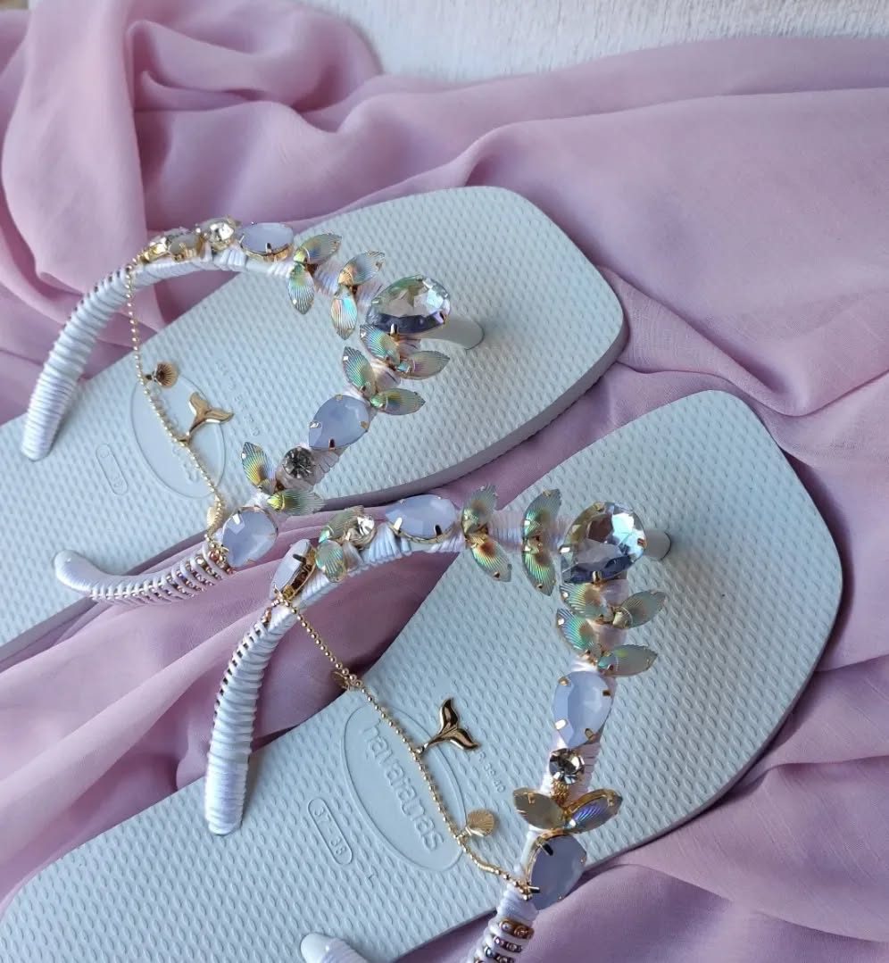 Chinelo branco com pedraria clara sobre tecido lilás
